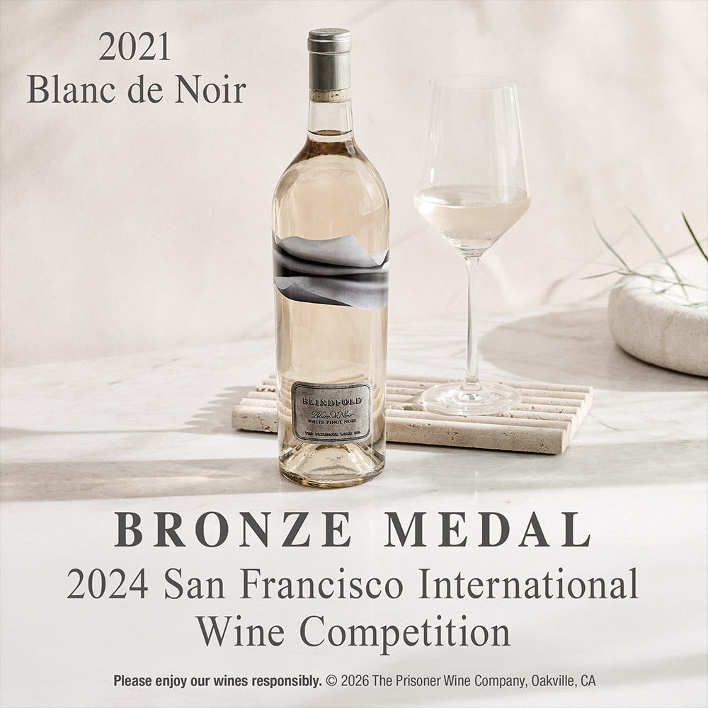 A bottle of 2021 Blanc de Noir wine from The Prisoner is shown alongside a wine glass on a light stone surface, with text reading 'BRONZE MEDAL 2024 San Francisco International Wine Competition'.
