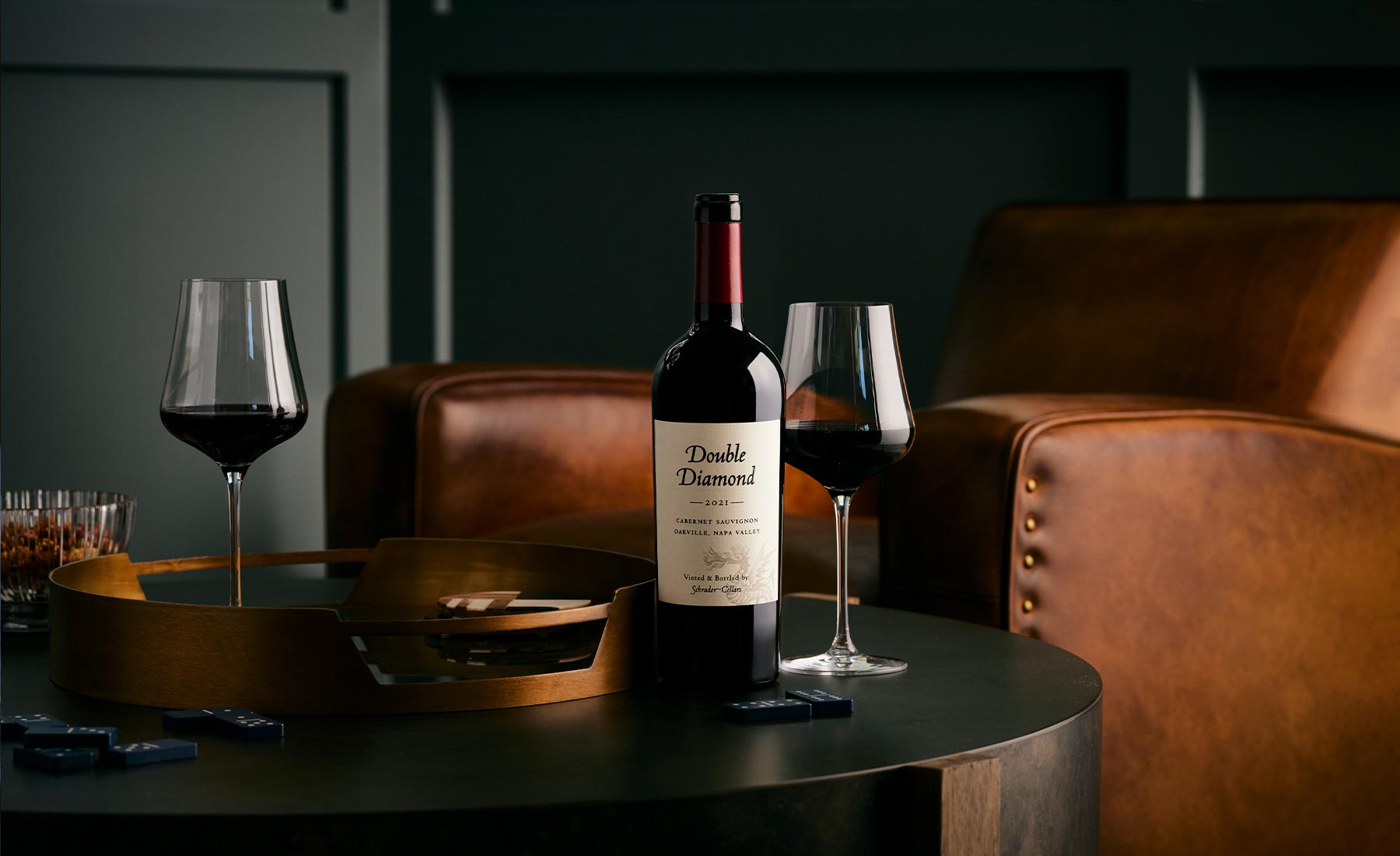 Double Diamond wine bottle with two glasses on a table in a dimly lit room.