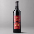 A bottle of Ode to Soul Red Wine with a black glass body, a dark gray capsule, and a red label featuring gold and white text. 