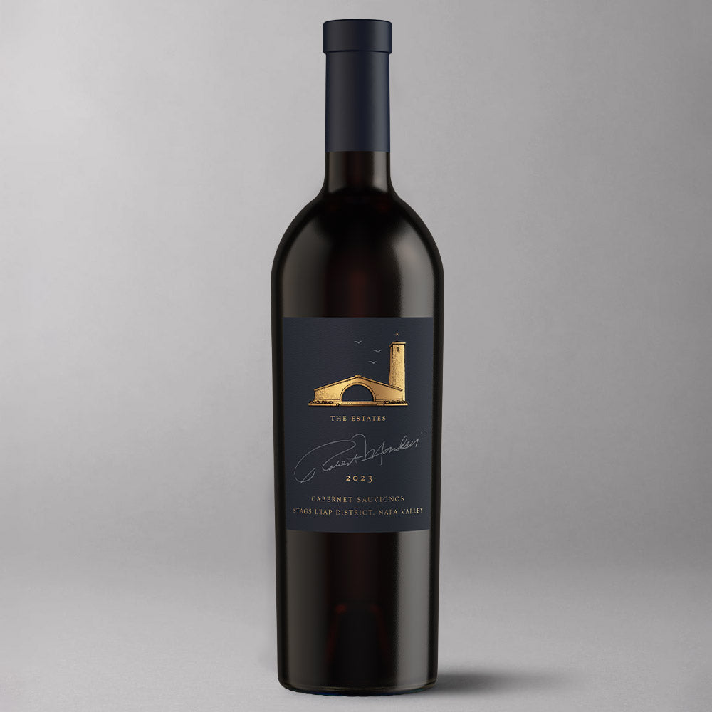 A bottle of Robert Mondavi Winery The Estates Cabernet Sauvignon  Clone 685, featuring a dark charcoal label with a gold arch illustration, set against a neutral gray background.