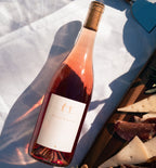 A bottle of 2023 Harvey & Harriet Rose laying label side up on a table with a charcouterie board next to it
